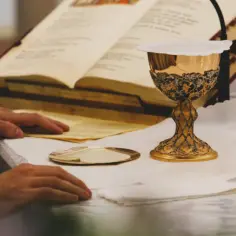 Złoty kielich i księga liturgiczna na ołtarzu, przygotowane do mszy za zmarłego.