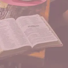 Otwarta księga Koheleta, tekst biblijny, leży na stole obok notatek.