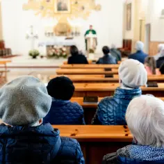 Widok zza pleców osób siedzących w kościele, w stronę ołtarza.
