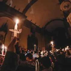 W kościele trwa nabożeństwo nieszpory za zmarłego. Ludzie trzymają zapalone świece, tworząc podniosłą atmosferę.