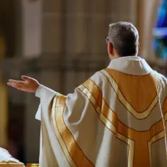 Kapłan w złotej dalmatyce, z rękami rozłożonymi, przygotowuje się do procesji z darami.