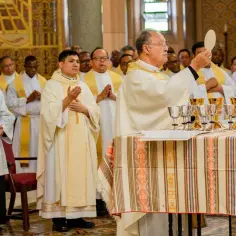 Kapłani w szatach liturgicznych podczas mszy świętej wieczystej. Na stole kielichy i hostia.