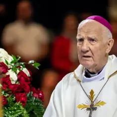 Starszy biskup w szacie liturgicznej, z różowym piuską na głowie, obok bukietu czerwonych róż i białych kwiatów. Tytuł biskupów w liturgii greckiej.