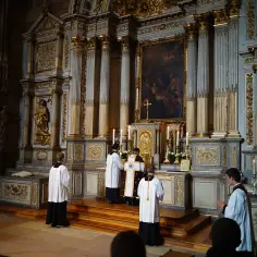 Uroczysta pierwsza modlitwa eucharystyczna w kościele. Kapłani w szatach liturgicznych przy ołtarzu.