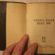 Otwarta książeczka z napisem "CZĘŚCI STAŁE MSZY ŚW.". Widoczny fragment okładki i strony z tekstem.