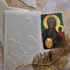 Opłatek z sceną narodzenia Jezusa, ikona Matki Boskiej z Dzieciątkiem i złoty liść. Symbolika modlitwy przed wieczerzą wigilijną.