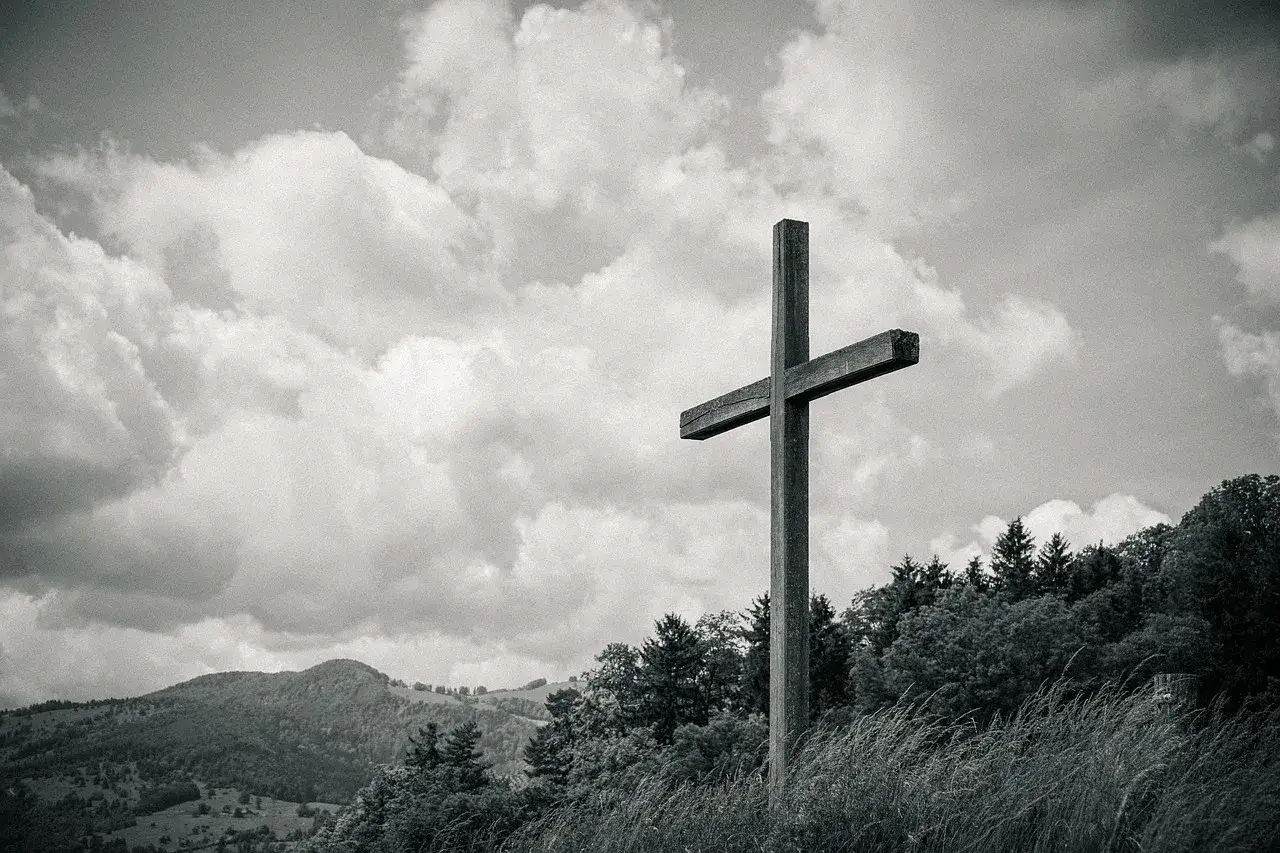Drewniany krzyż na tle burzowych chmur, symbol nadziei w walce Dawida z Goliatem.